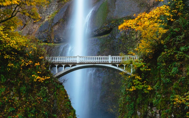 a white bridge with a waterfall backdrop